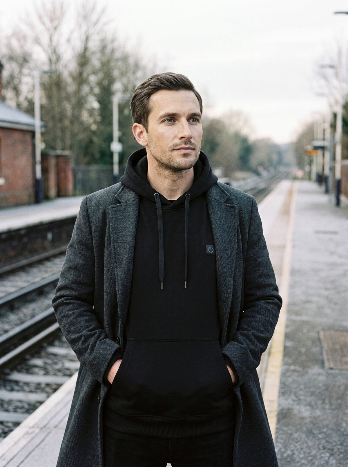 Heated Hoodie Unisex – Black – worn on a station platform