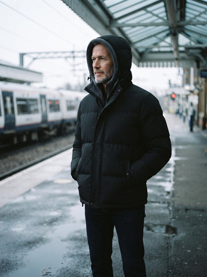 Men's Fleece Lined Hooded Puffer Jacket – Black – hood up on a railway platform