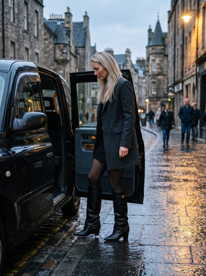 Women's Slouchy Knee High Boots – Black Skin – worn with a skirt on a wet evening street